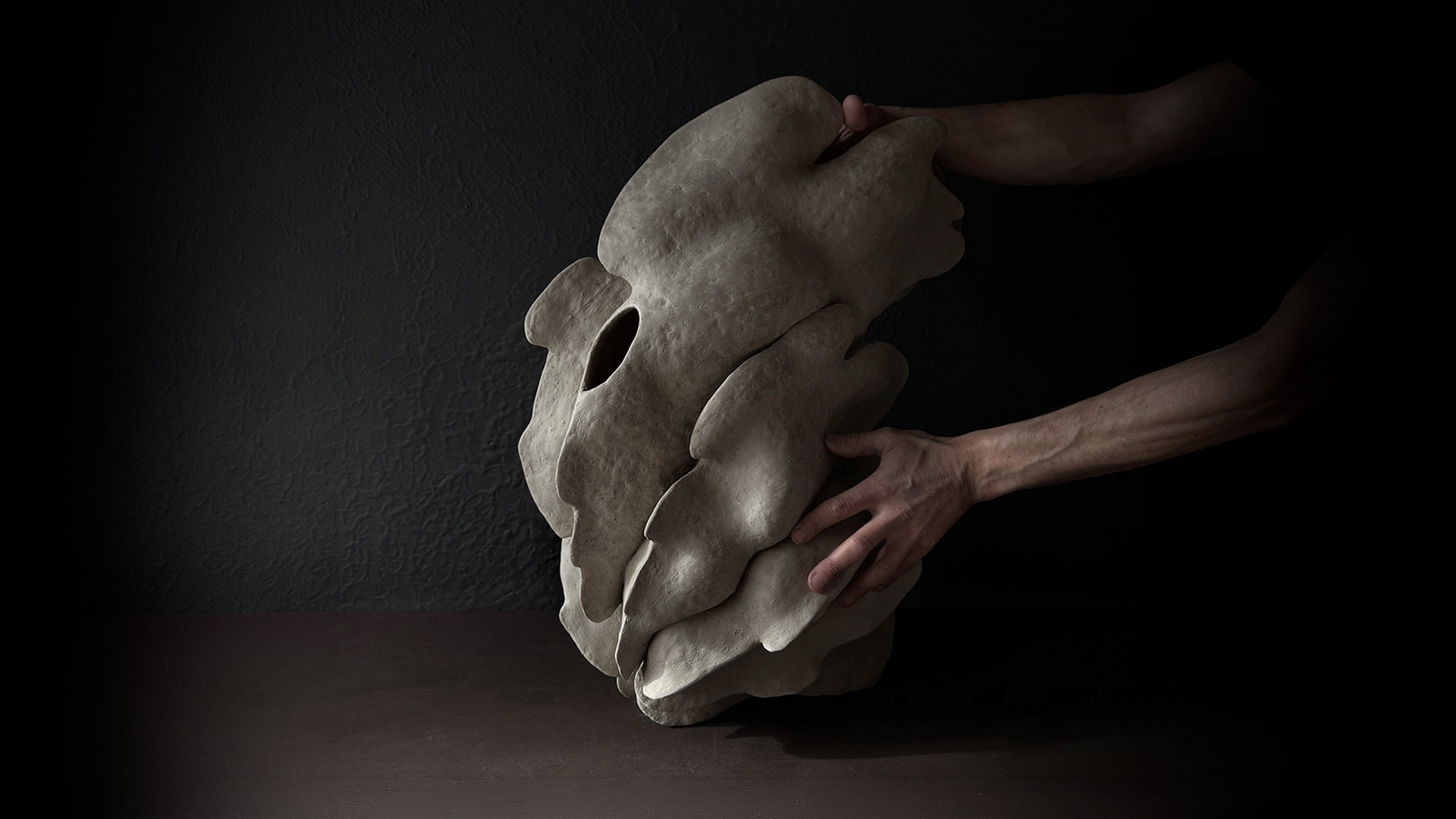 Dark ceramic sculpture held by the artist