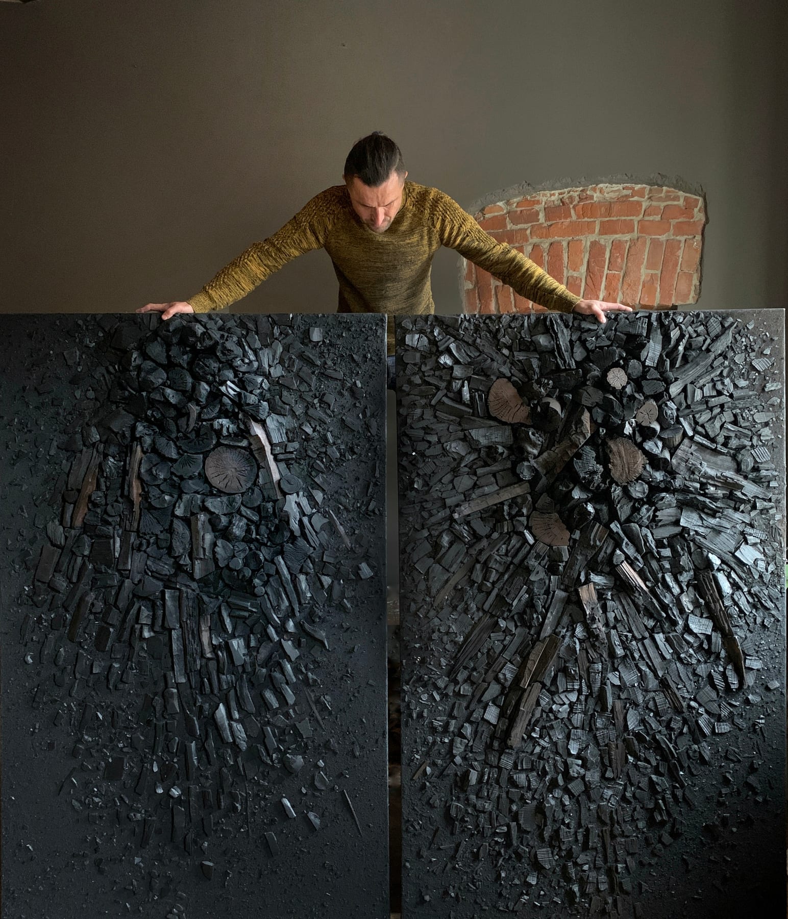 Artist standing behind dark wall panels by Voznicki